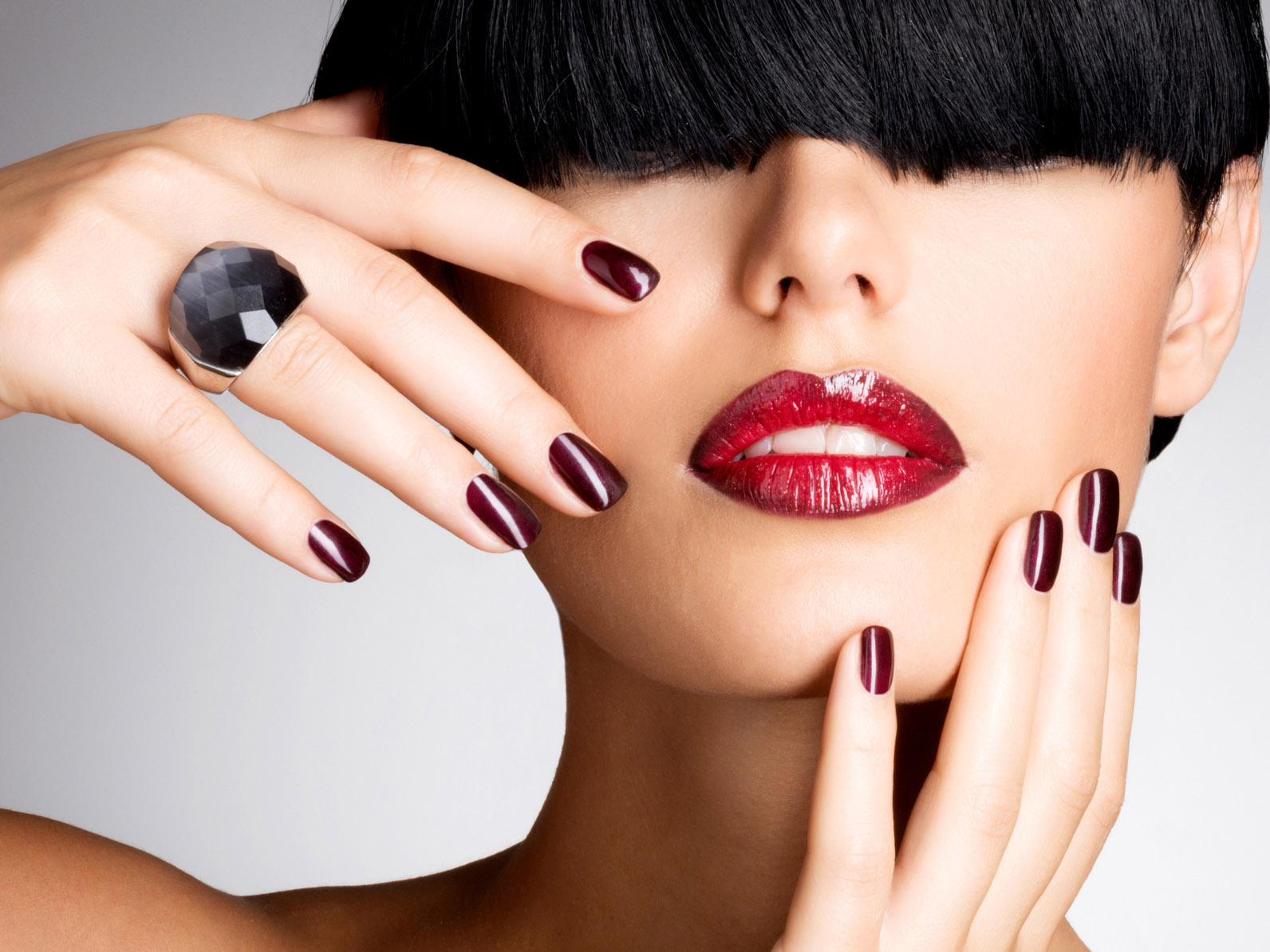 Closeup face of a woman with beautiful sexy red lips and dark nails - studio